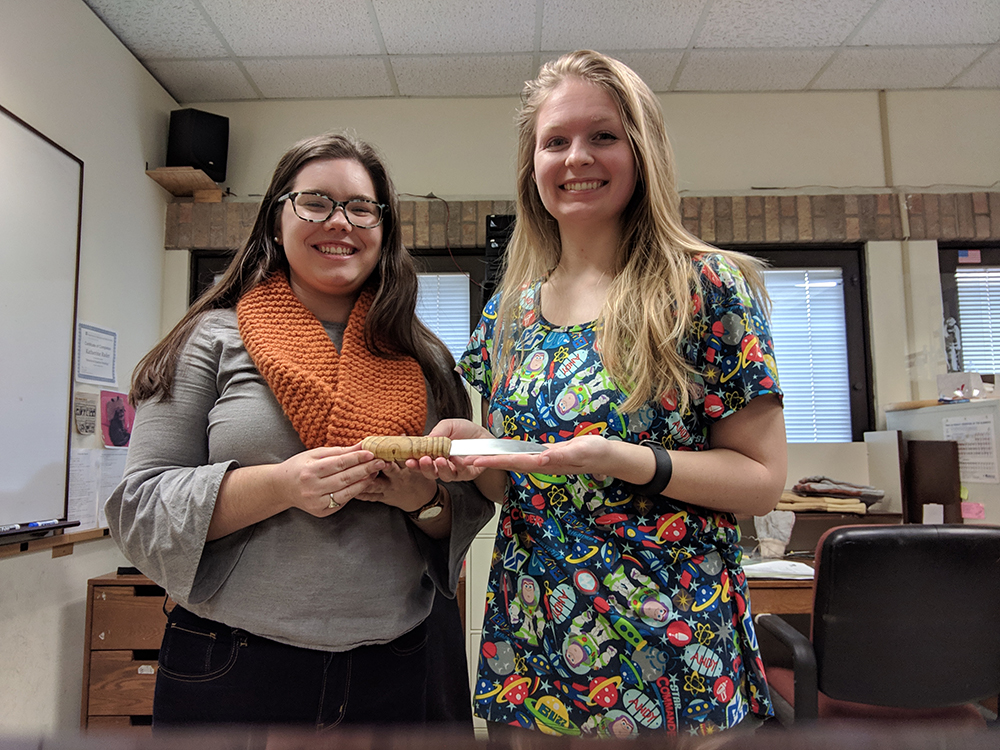 two female students standing and holding fabricated project